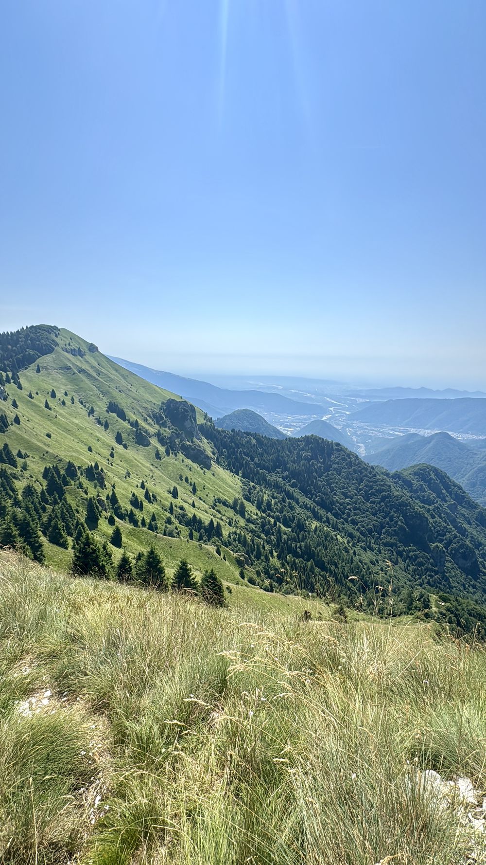 La stessa cresta d'estate, con i prati verdi e la pianura che si apre in fondo.